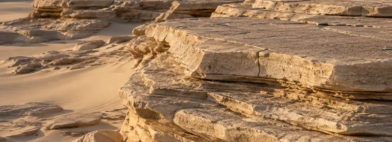 Layered desert rock and wind-shaped sand.